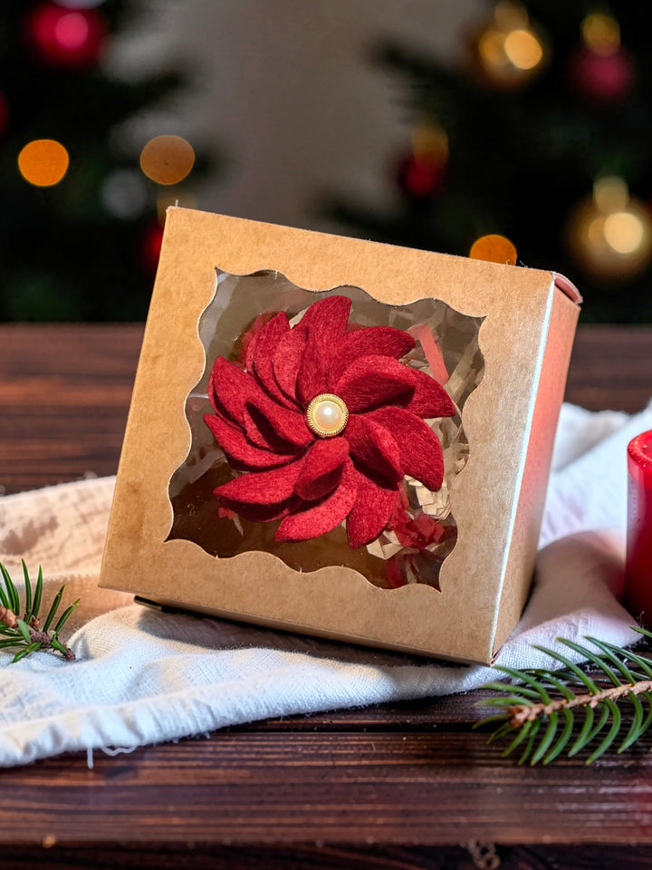 Cranberry red merino wool felt poinsettia Christmas brooch with a pearl and gold centre, in a windowed kraft gift box