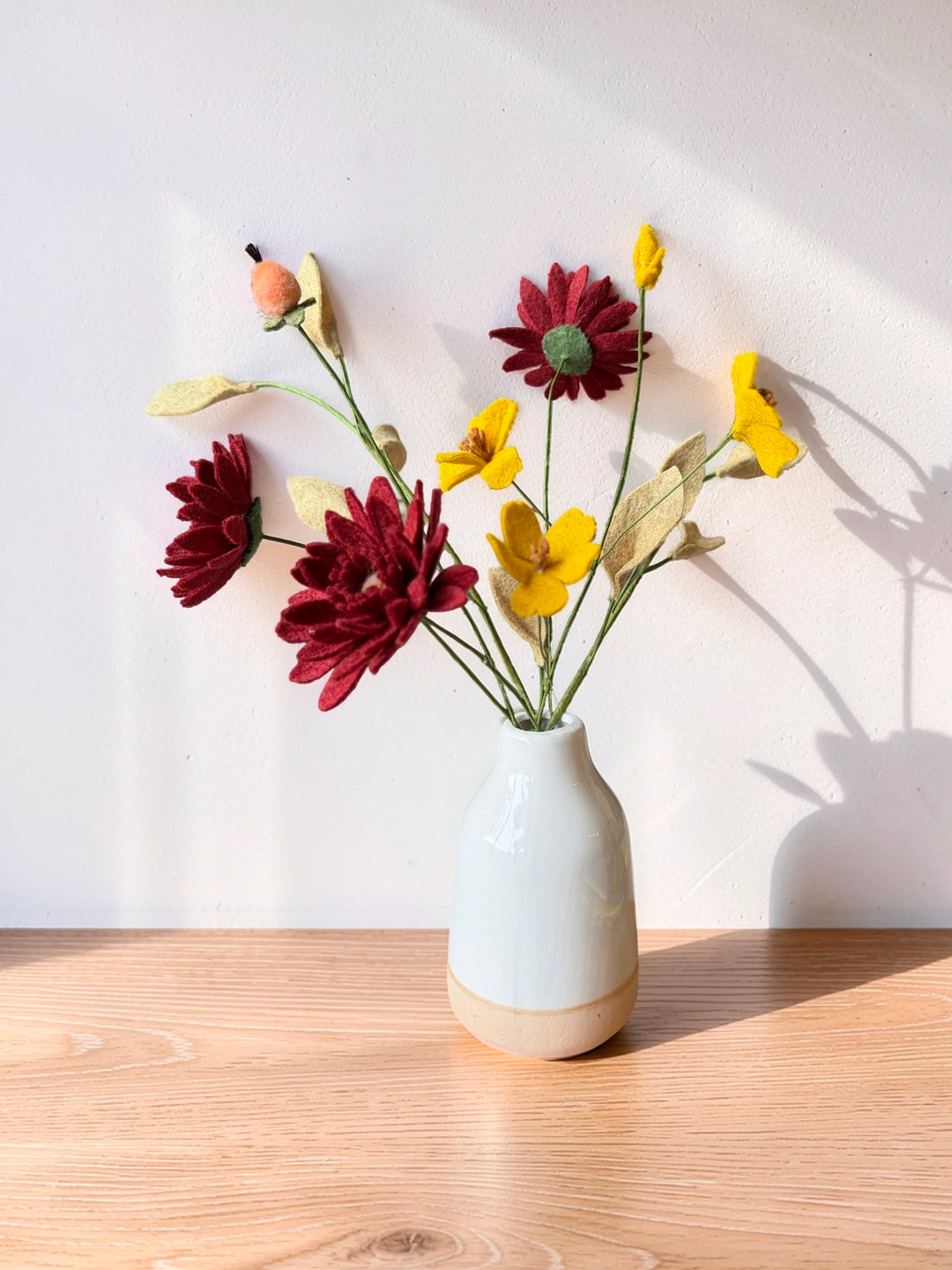 Hand-cut Merino wool felt autumn bouquet in a ceramic vase, close-up view